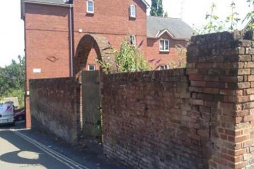 Arched gateway into the graveyard and the poor state of the walls