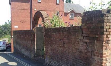 Arched gateway into the graveyard and the poor state of the walls